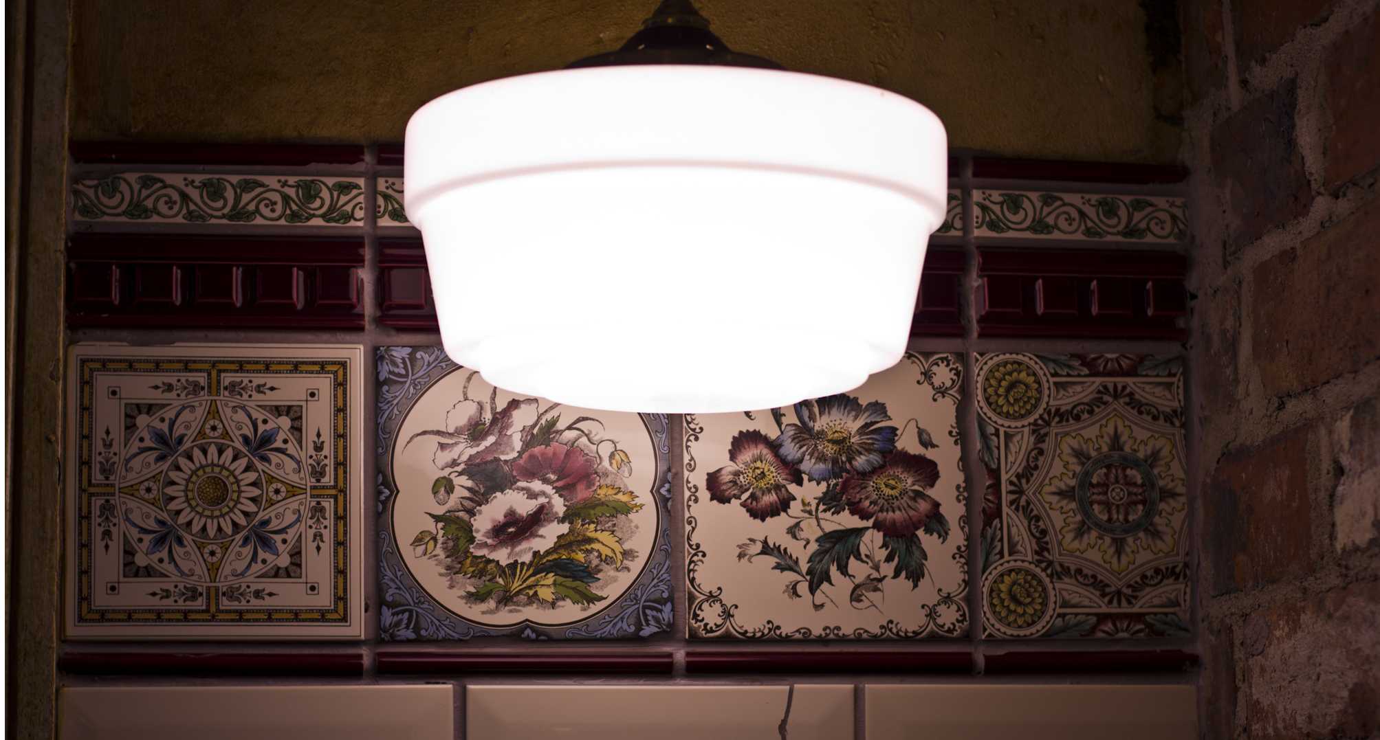 Decorative floral patterned wall tiles in warm brown and cream tones, softly lit by a frosted pendant light