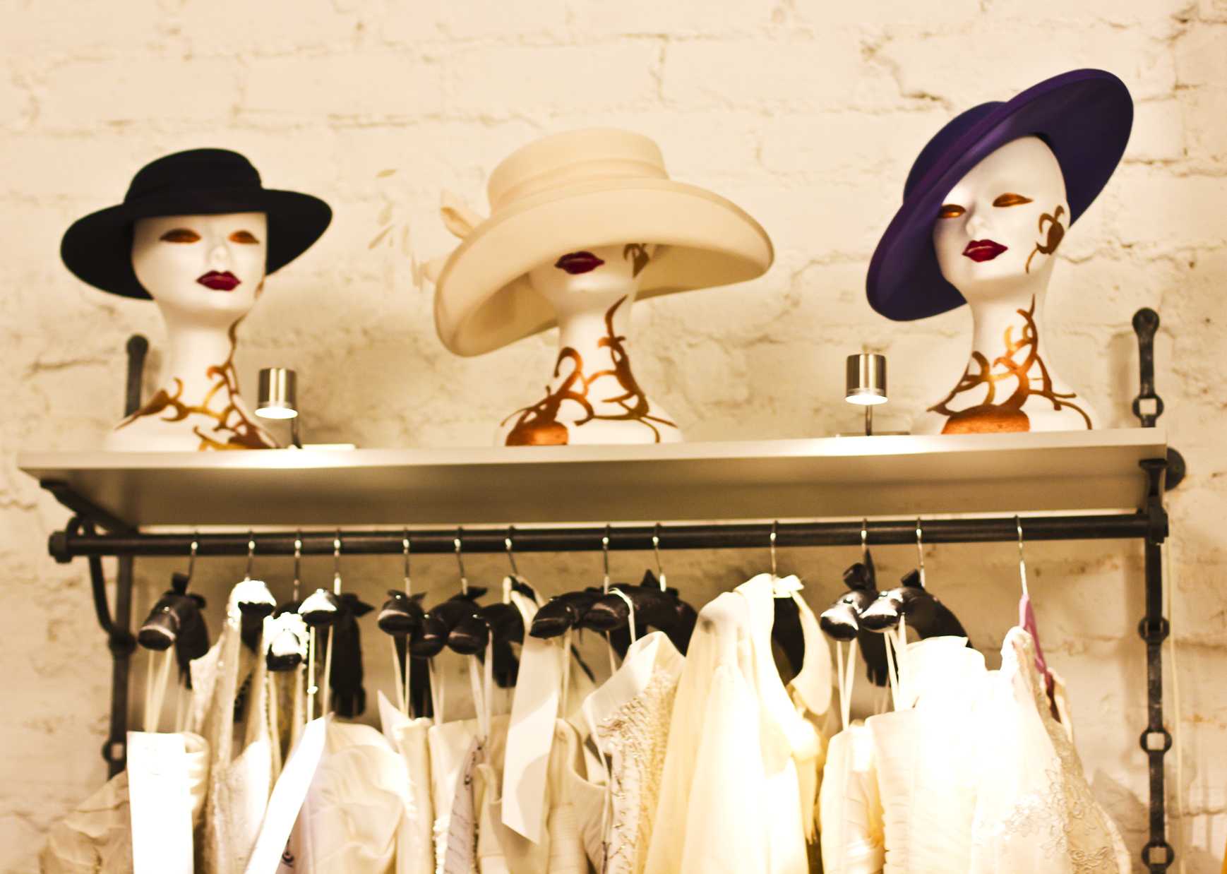 Three wide-brimmed hats in black, cream, and muted purple lined up against a dark grey studio backdrop